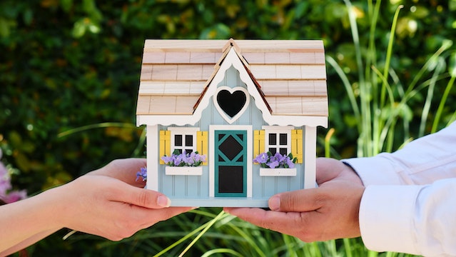 People holding a miniature house.