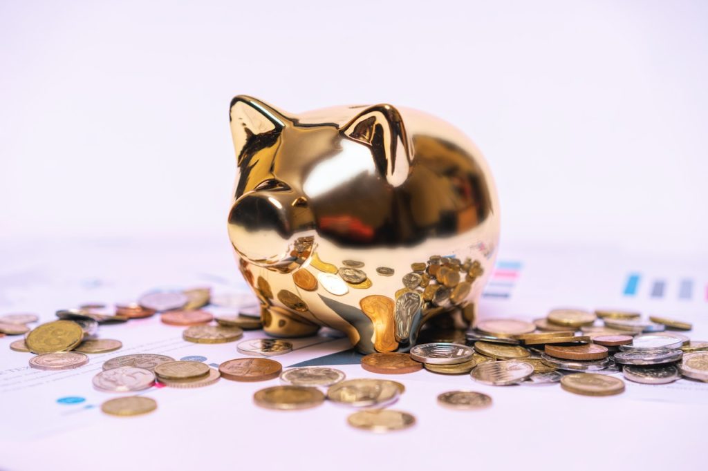 A golden piggy bank on top of various coins.